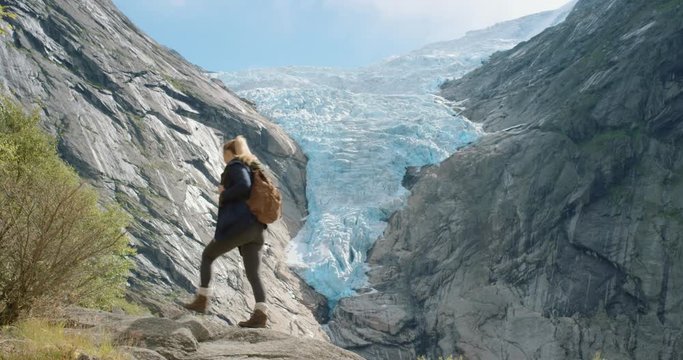 Woman with arms raised looking melting glacier view Hiking Girl lifting arm up celebrating scenic landscape enjoying vacation travel adventure nature Norway