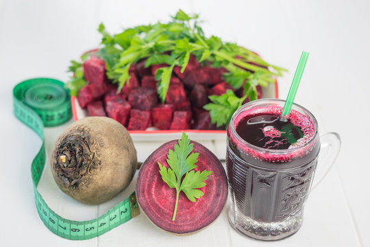 Measuring tape, beet juice and parsley on white wooden table.