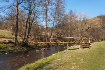 Wooden footbridge over the river in the country. Spring time in nature. Czech Republic.