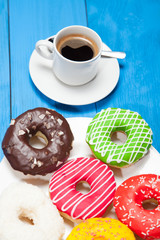Cup with coffee and donuts on a blue wooden table