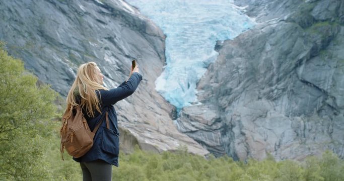 Brave explorer Woman taking panorama photograph of melting glacier with smartphone photographing Climate change concept landscape nature background view enjoying vacation travel trekking adventure