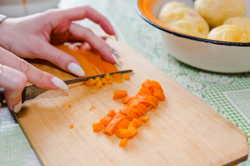 The woman cuts vegetables on salad.