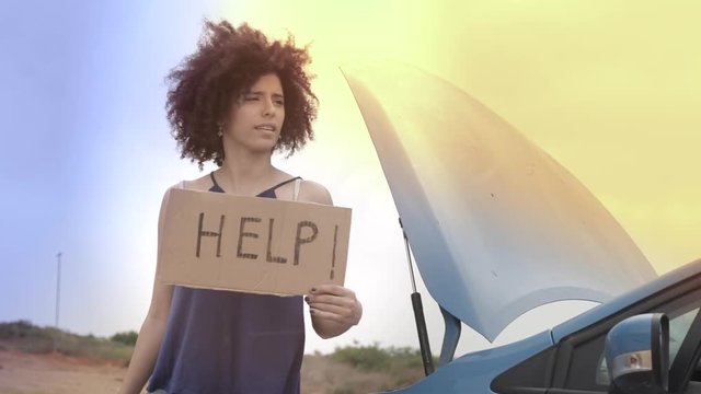 Young multirace model with help sun next to broken car