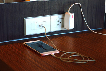 Mobile phone charging with usb chager plugged on wooden pole