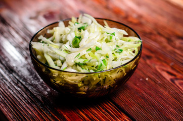 Salad with the cabbage and green onion on wooden table