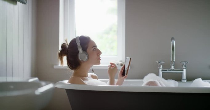Beautiful Woman listening to music  in bathtub enjoying relaxing bubble bath lifestyle real natural body care concept