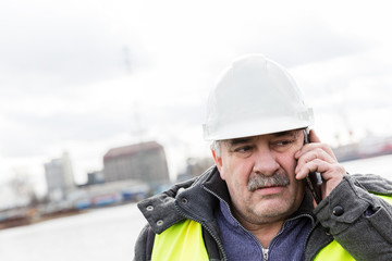 Senior engineer builder on the phone at construction site.