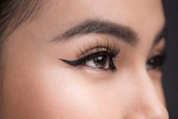 Perfect shape of eyebrows. Beautiful macro shot of female eye with classic eyeliner makeup.