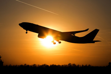 airplane taking off at sunset on
