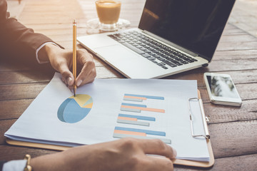 Business woman analyzing graph document with laptop and cell phone vintage tone.