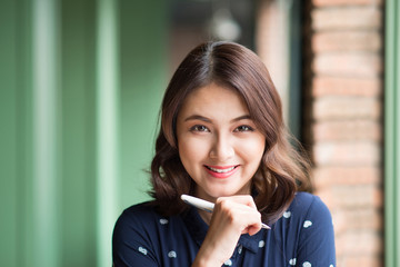 Young beautiful woman in the cafe near the window, thinking and writing something.