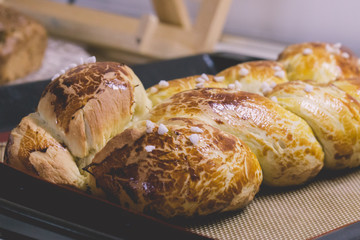 Freshly baked hot artisan bread beautifully decorated as a braid with golden crust straight out of the oven, cooling down