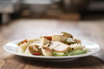 caesar salad with cherry kumato tomatoes on wooden table, homemade dish