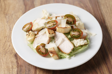 caesar salad with cherry kumato tomatoes on wooden table, homemade dish