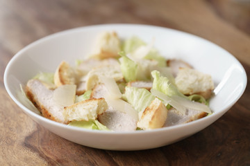 caesar salad with chicken on wooden table, homemade dish