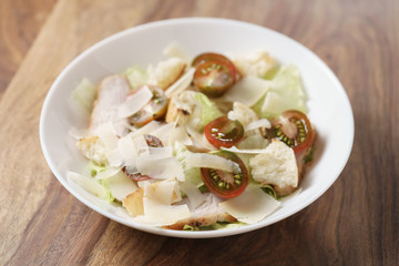 caesar salad with cherry kumato tomatoes on wooden table, homemade dish