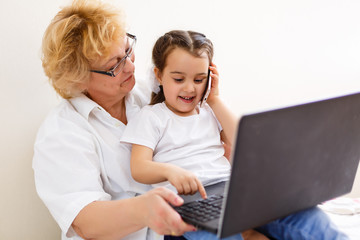 Asian grandmother and granddaughter looking at laptop