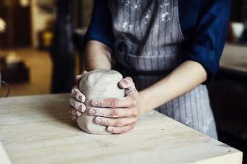 Woman hands close-up, forming crude clay in a potter's workshop studio. Craft-work