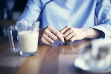 Fototapeta na wymiar Woman hands close-up, lady wearing blue shirt having coffee in cafe or restaurant alone, loneliness