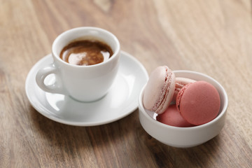 cup of fresh espresso with macarons on wood table, shallow focus
