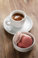 cup of fresh espresso with macarons on wood table, shallow focus