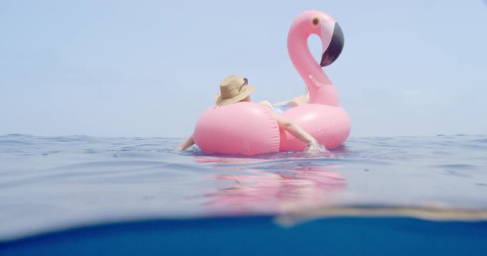 Woman lying on inflatable flamingo floating in middle of ocean girl relaxing in summer sunshine enjoying tropical vacation