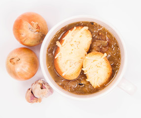 Onion soup with toast on a white background with some onions and garlic