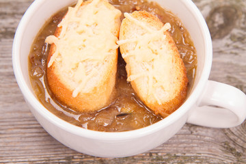 Onion soup with toast on a wooden background