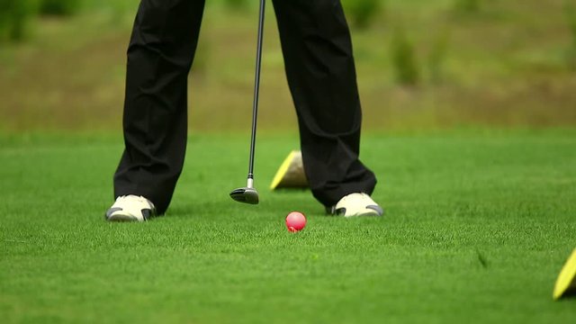 Golfer on course doing golf swing, leg and club shot only