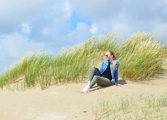 Fototapeta na wymiar junge Frau entspannt in den Dünen an der Nordsee