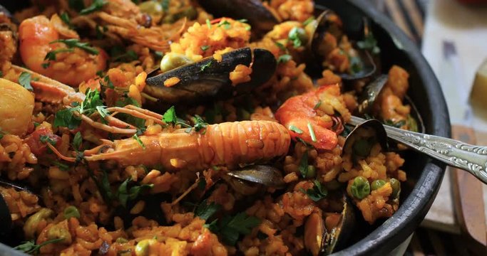 Dolly close up panning view of a Spanish seafood paella: mussels, king prawns, langoustine, haddock