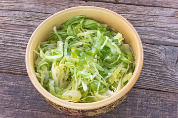 Sliced young cabbage salad in ceramic bowl on table