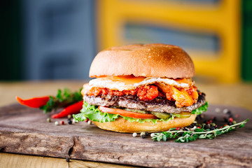 Homemade traditional burger with beef, egg, tomato, cheese and lettuce on textured background. Fast food concept. Copy space