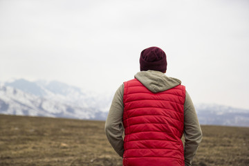 back of man in red waistcoat on the mountains background