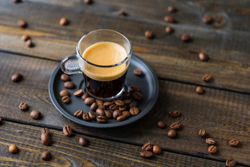 A cup of espresso and coffee beans on a wooden table