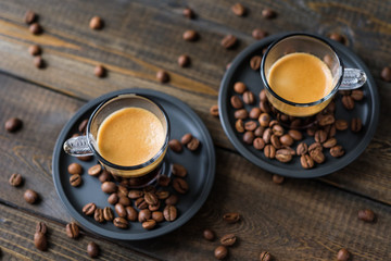 Two cups of espresso and coffee beans on a wooden table