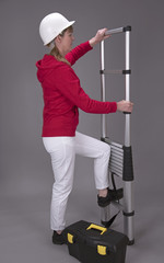 Female worker wearing a hard hat and holding a telescopic ladder