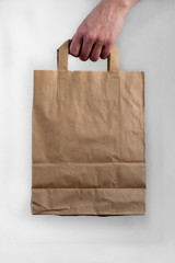 Hand holding paper grocery bag