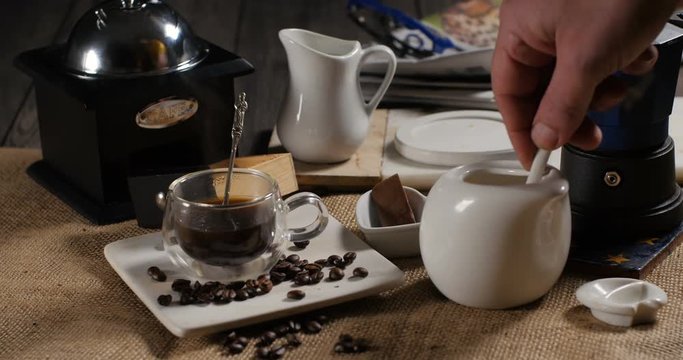 Adding sugar to a hot cup of coffee from a traditional Italian coffee machine