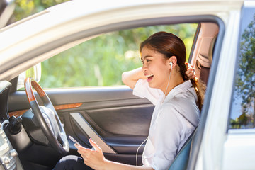 Close up portrait of happy young asian woman sitting in car talking on cellphone