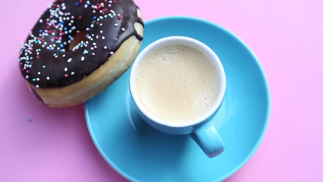 blue cup of coffee with chocolate donut on rotating pink plate
