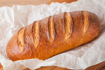 Delicious homemade wheat loaf on paper closeup