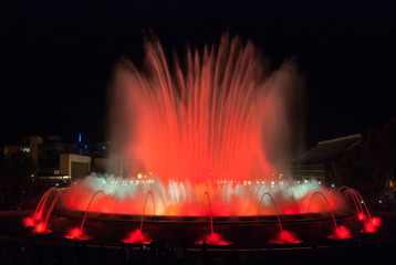 A crowd of people at colourful light & water fountain show.  Night at Magic fountain in Barcelona. Large attraction turns on at night & provides entertainment for all ages on a warm evening. 
