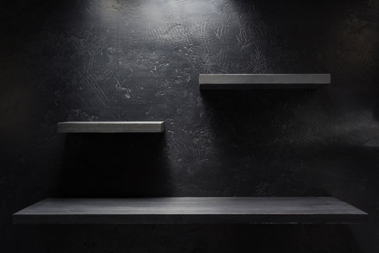 wooden shelf at black wall
