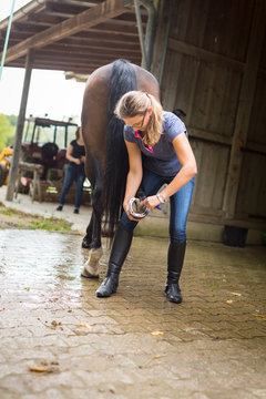 Woman Checking Her Horse's Hooves