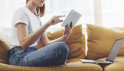 Naklejka premium Hipster girl using digital tablet and modern laptop while working on new project, Young beautiful woman studying online from home
