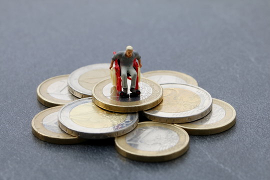 Rollstuhlfahrer auf Haufen Geld