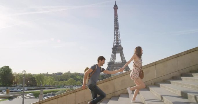 Young couple holding hands woman leading boyfriend walking towards view of Eiffel Tower Paris travel concept