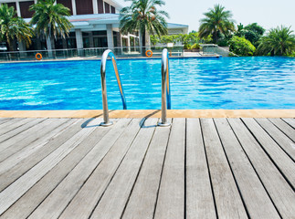 Swimming pool with stair and wooden deck at hotel.