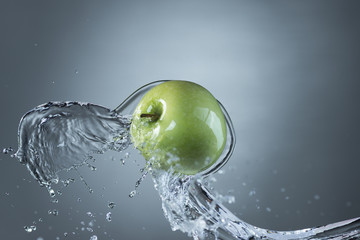 Green apple and water splash on gray background